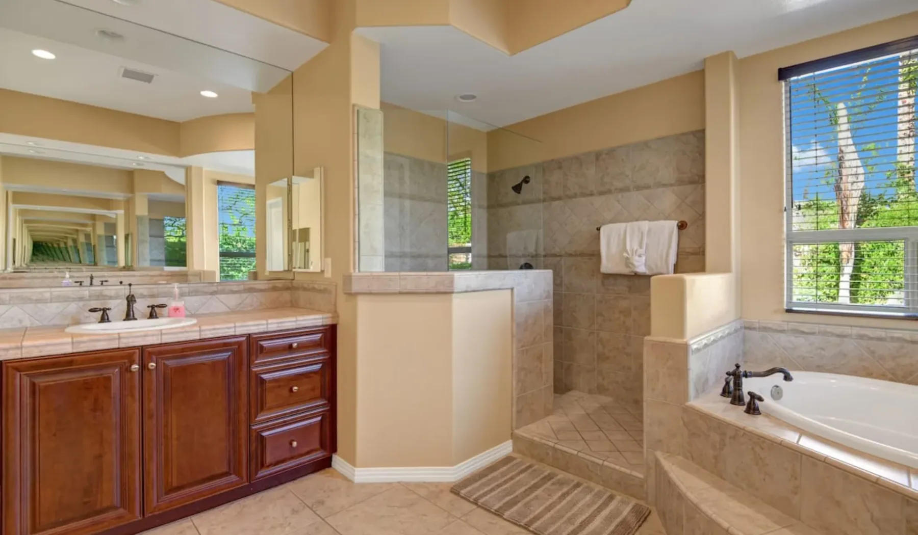 A bathroom with a long vanity, large mirror, and tiled shower area.