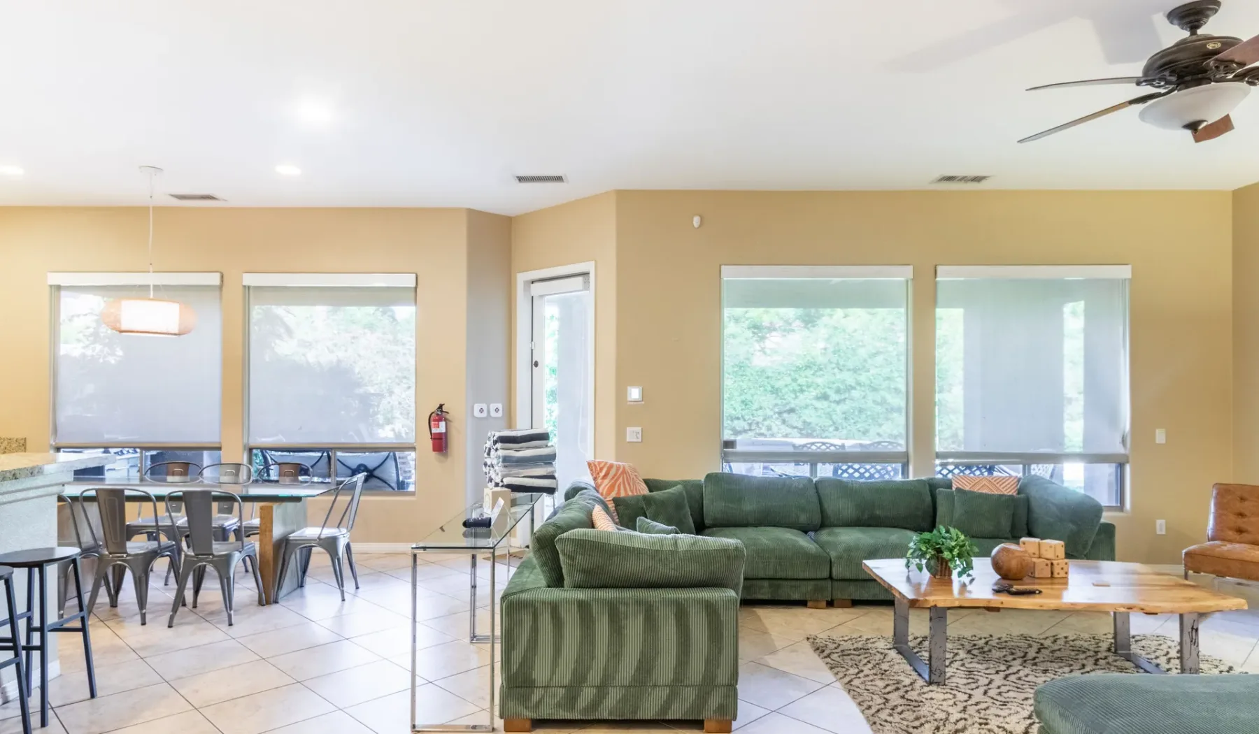 A bright open-plan living and dining area with green seating and a dining table.