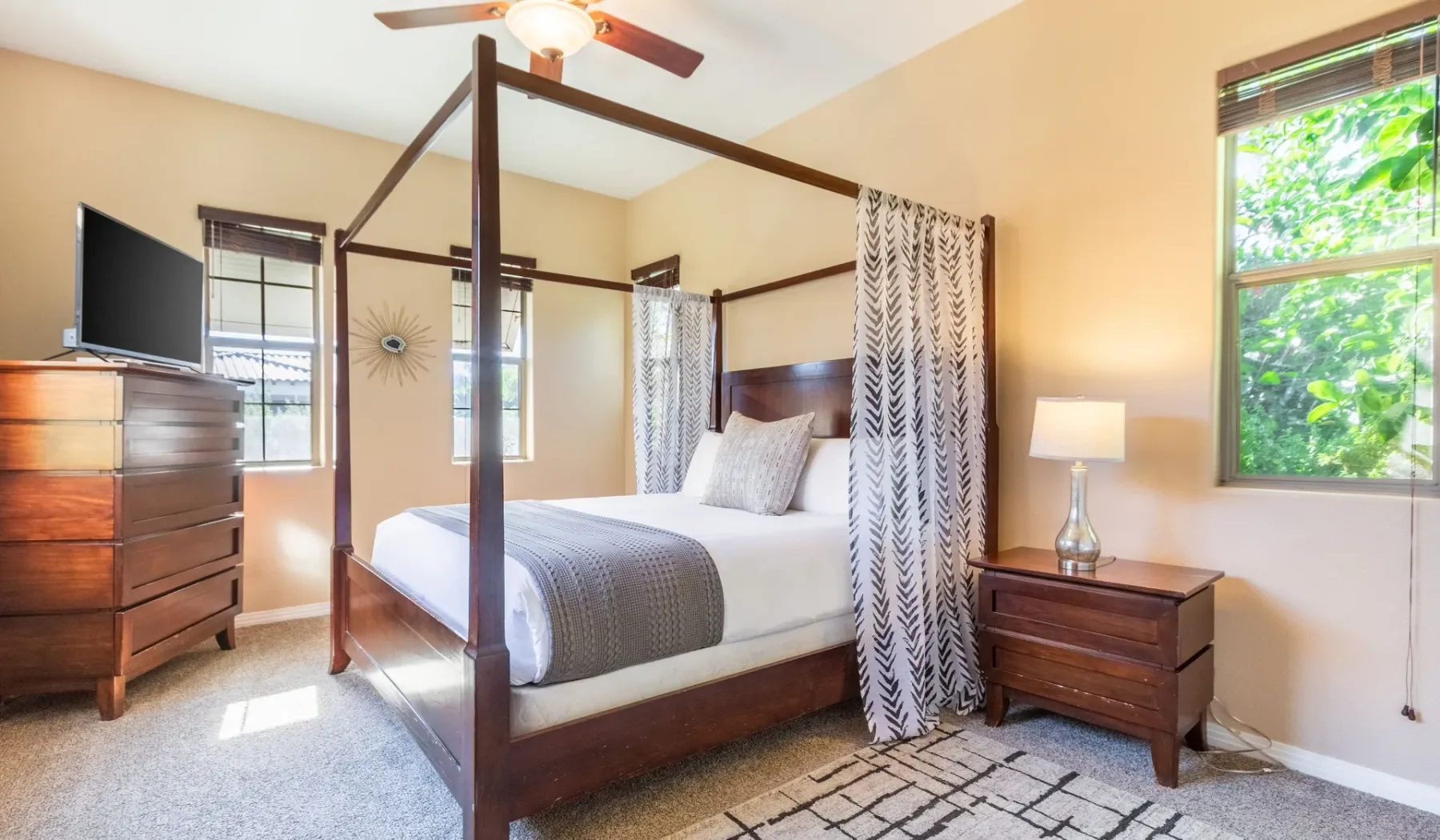 A bedroom with a wooden four-poster bed and bright windows.