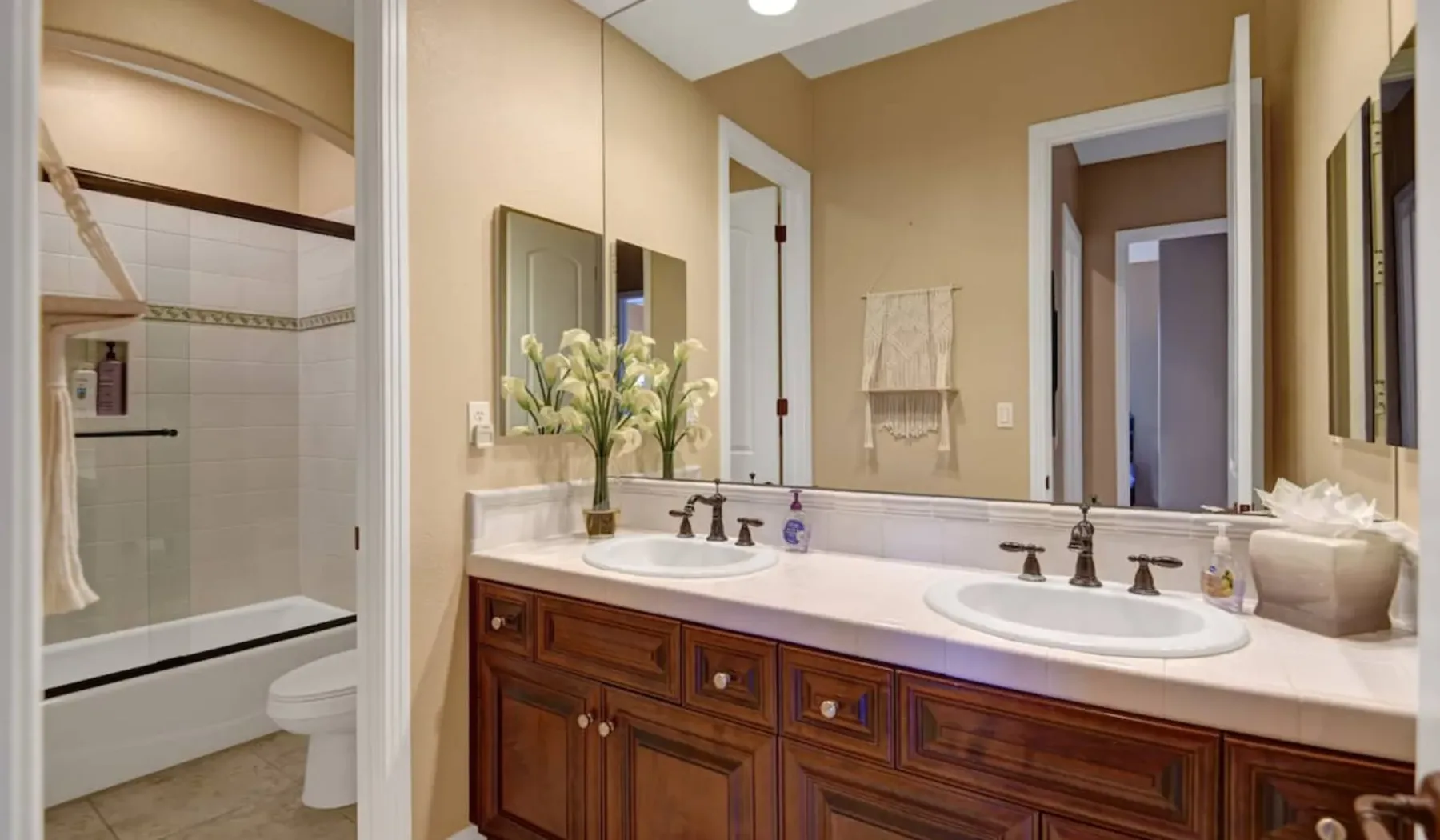 A bathroom vanity with two sinks and a large mirror faces a shower.