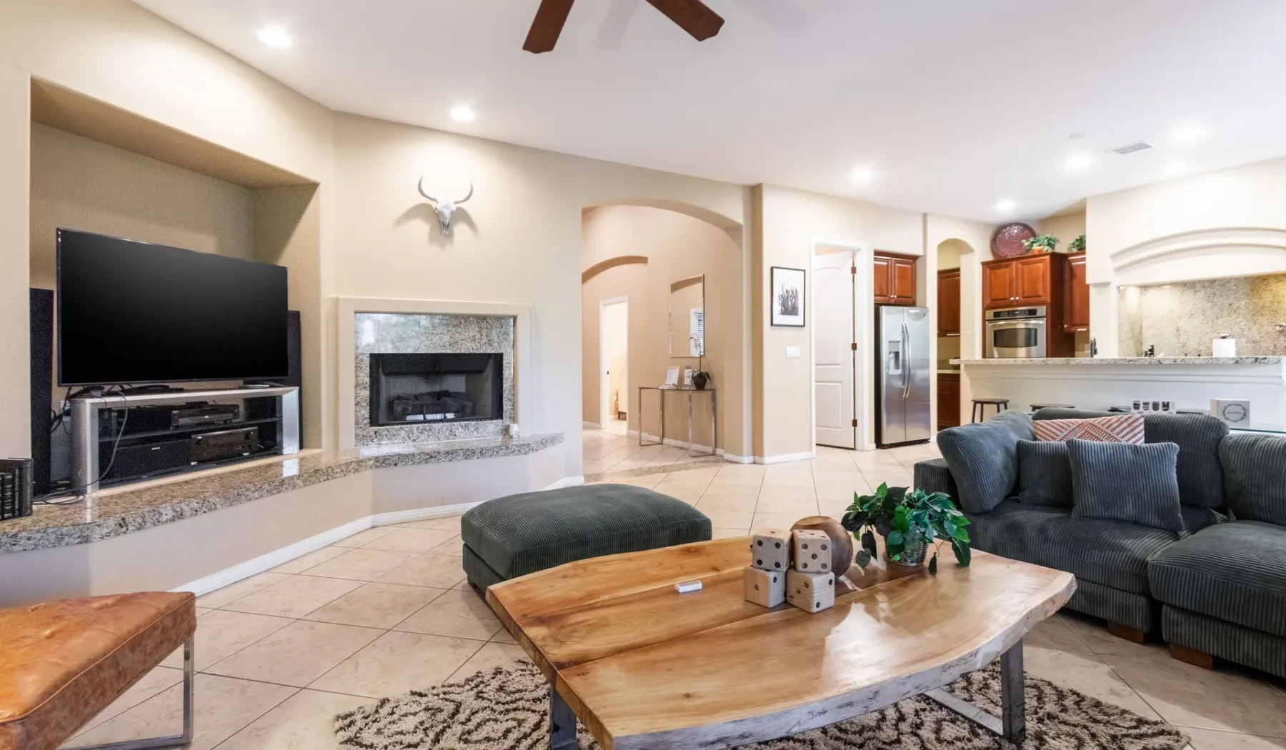 A living room opens into a kitchen, with seating around a wooden coffee table.