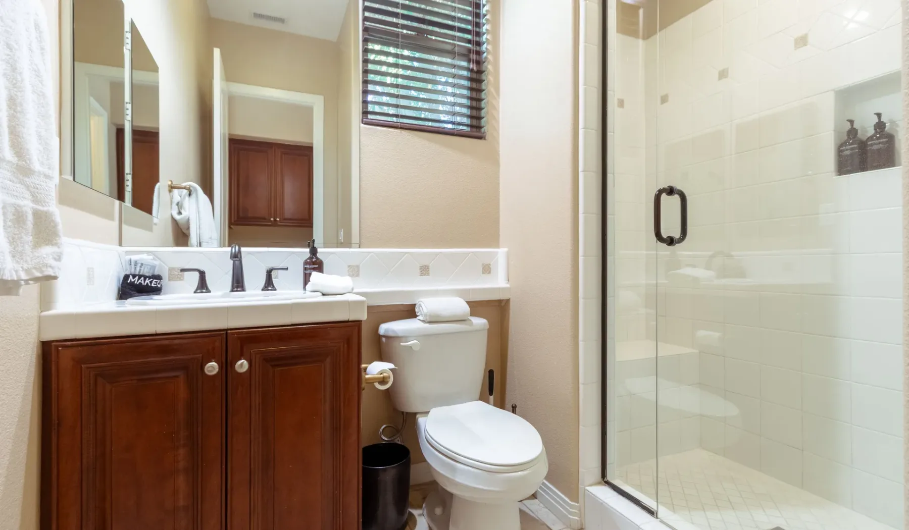 A bathroom with a wooden vanity, toilet, and glass shower.
