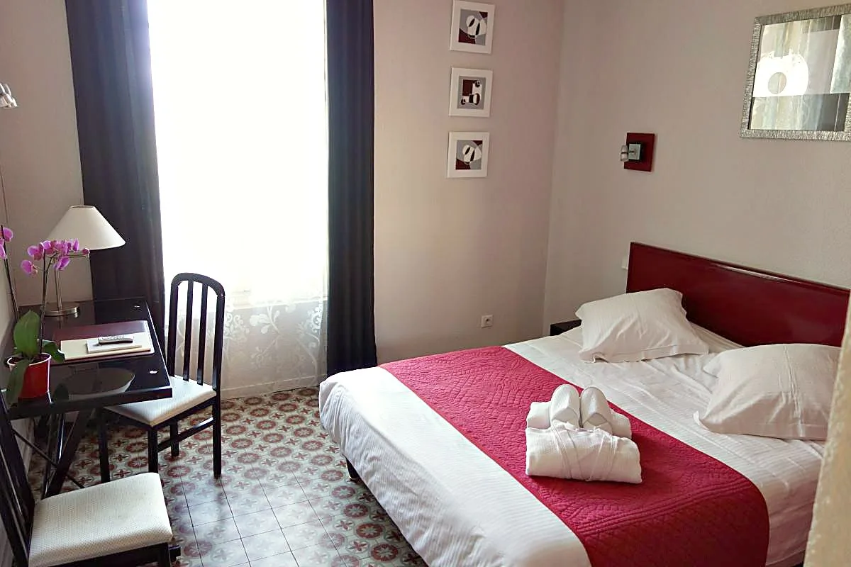 Guest room with fuchsia bedspread, desk and orchid