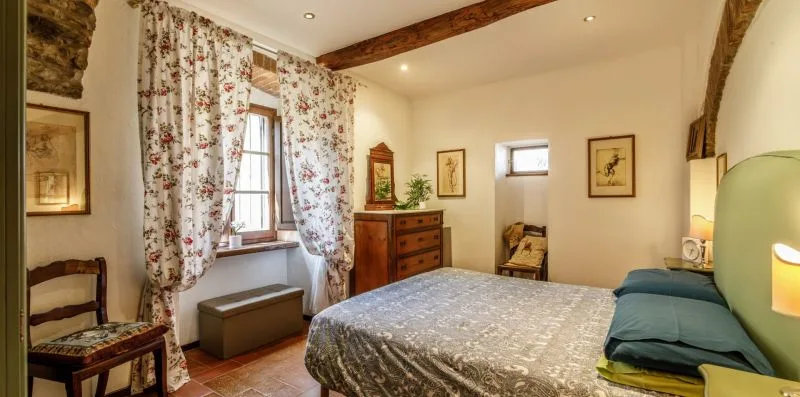 A bedroom with a bed, floral curtains, and framed artwork.