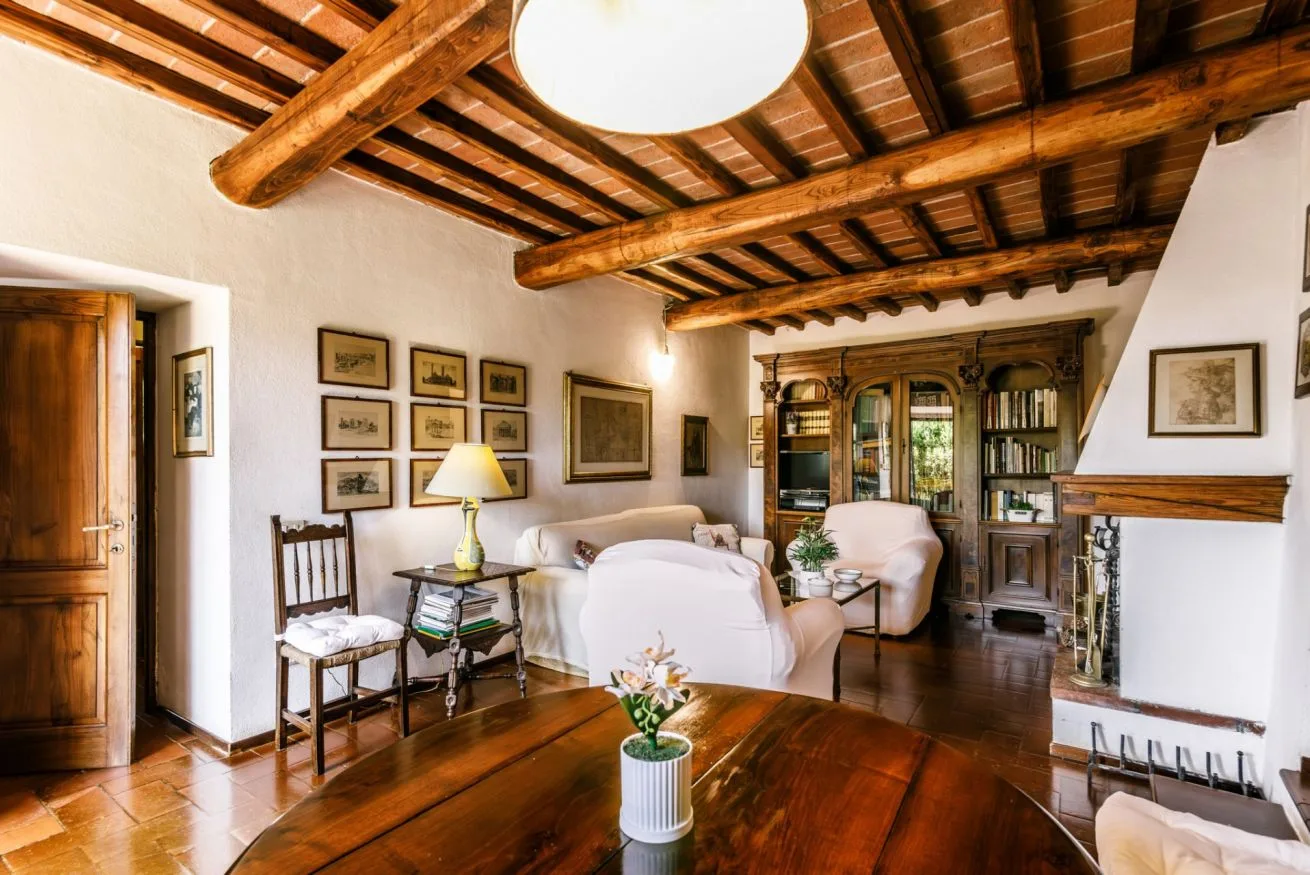 A living room with exposed wooden ceiling beams and seating around a coffee table.