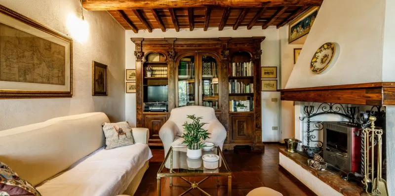 A traditional living room with seating, a wooden bookcase, and a fireplace.