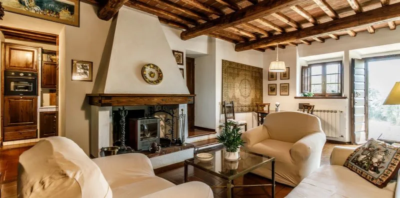 A living room with a fireplace, seating, and exposed wooden ceiling beams.