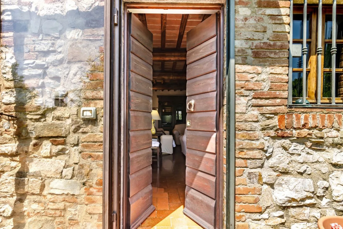 An open wooden doorway set in a stone wall reveals a room beyond.