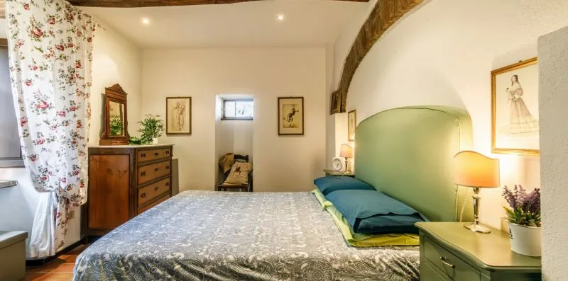 A bedroom with a bed, green headboard, and bedside table.