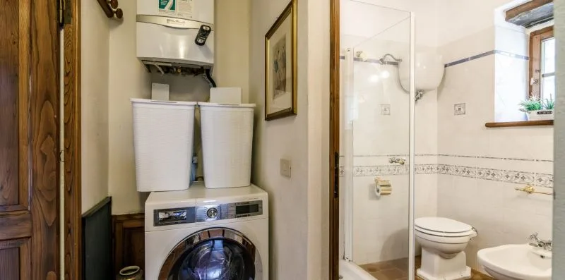 A laundry and bathroom area with a washing machine, toilet, and shower.