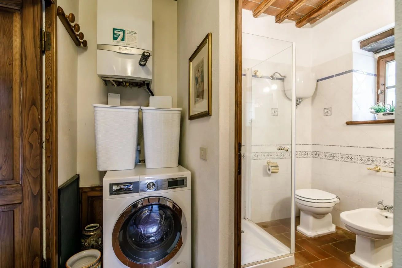 A bathroom with a washing machine and a glass shower.