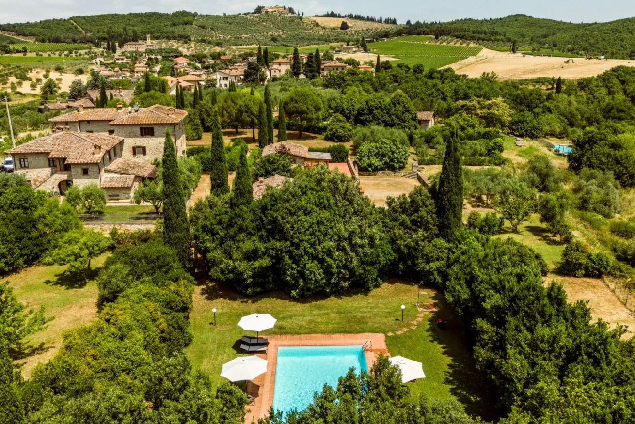 A swimming pool sits in a landscaped garden among trees and countryside.