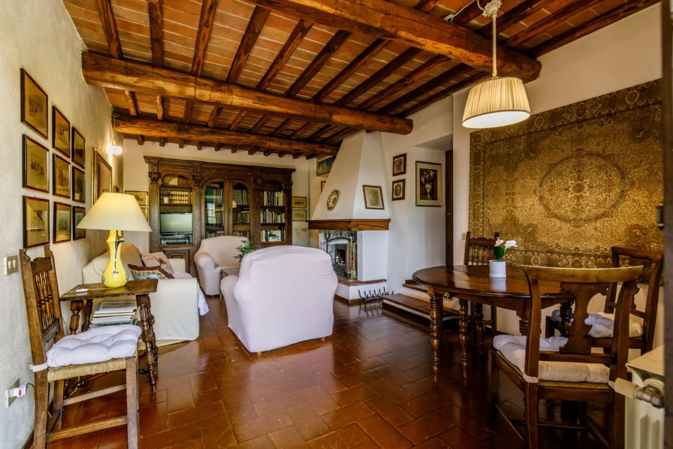 A living room with seating, a dining table, and exposed wooden ceiling beams.