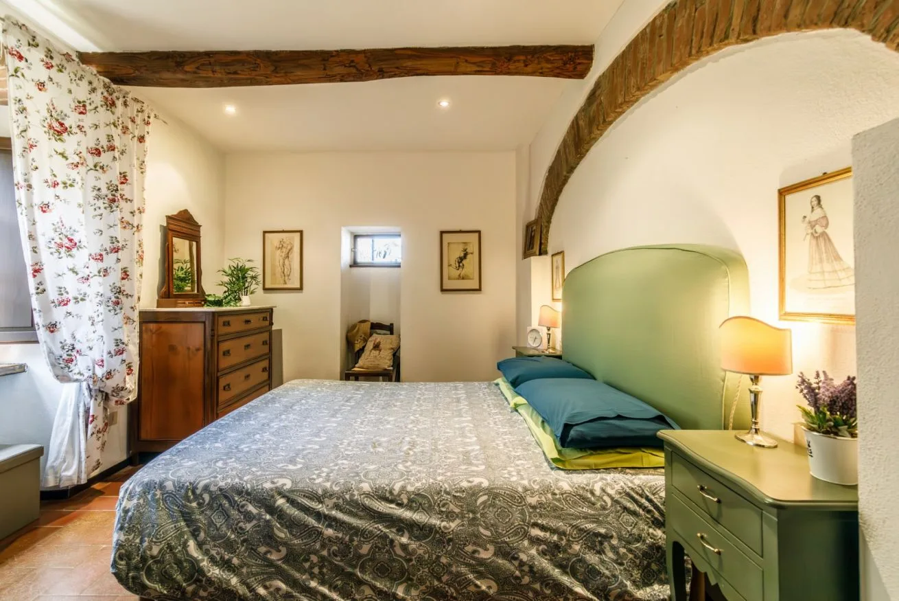 A bedroom with a large bed, green headboard, and floral curtains.