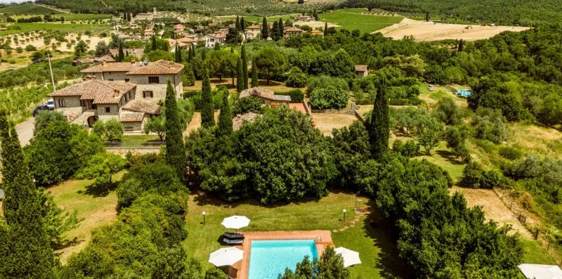 An aerial view of a countryside property surrounded by trees and fields.