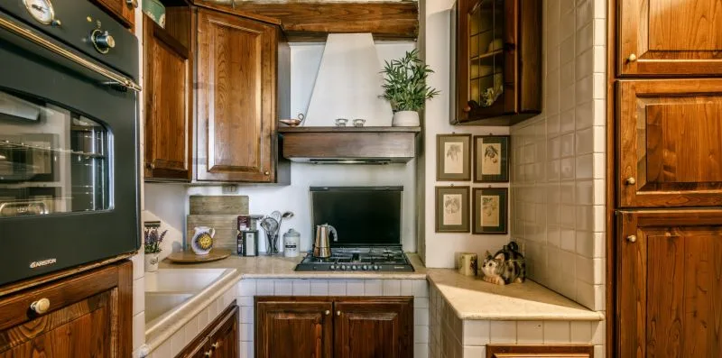 A compact kitchen with wooden cabinets, tiled counters, and a built-in oven.