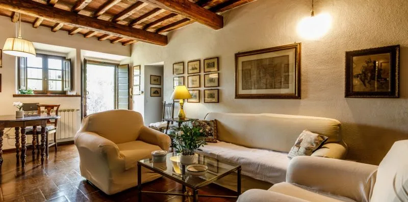A living room with sofas, an armchair, and framed pictures on the walls.