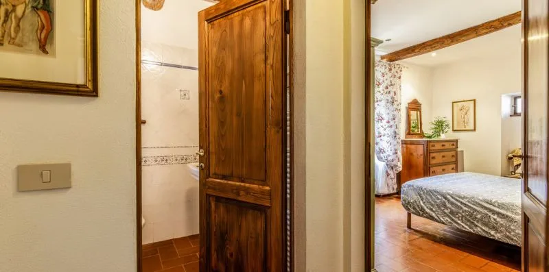 A bedroom is visible through an open doorway, with a bed and wooden dresser.