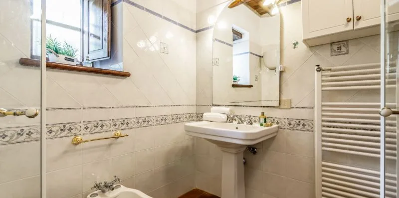 A tiled bathroom with a sink, mirror, and towel radiator.