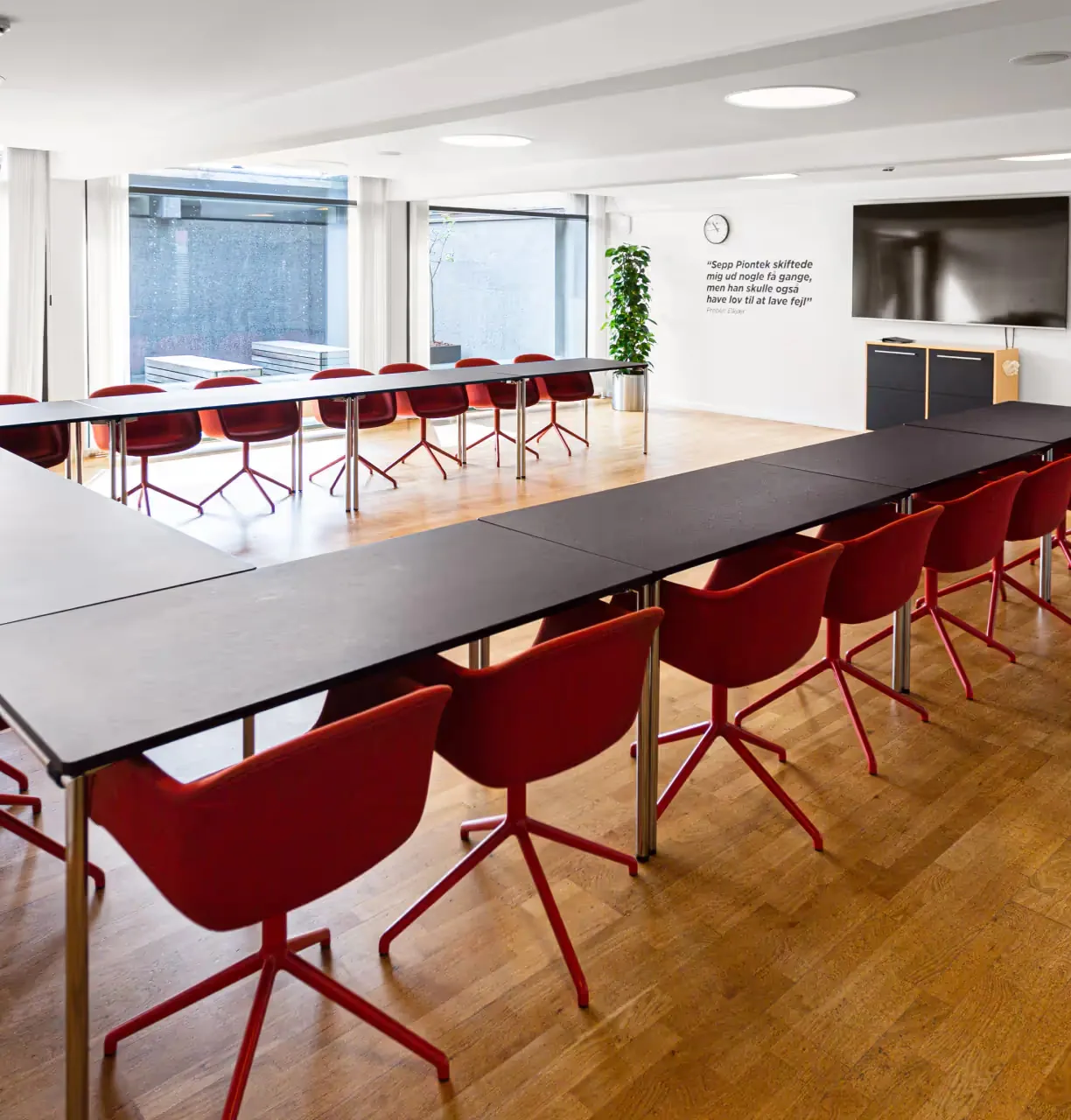 Conference room arranged with a horseshoe table and red chairs