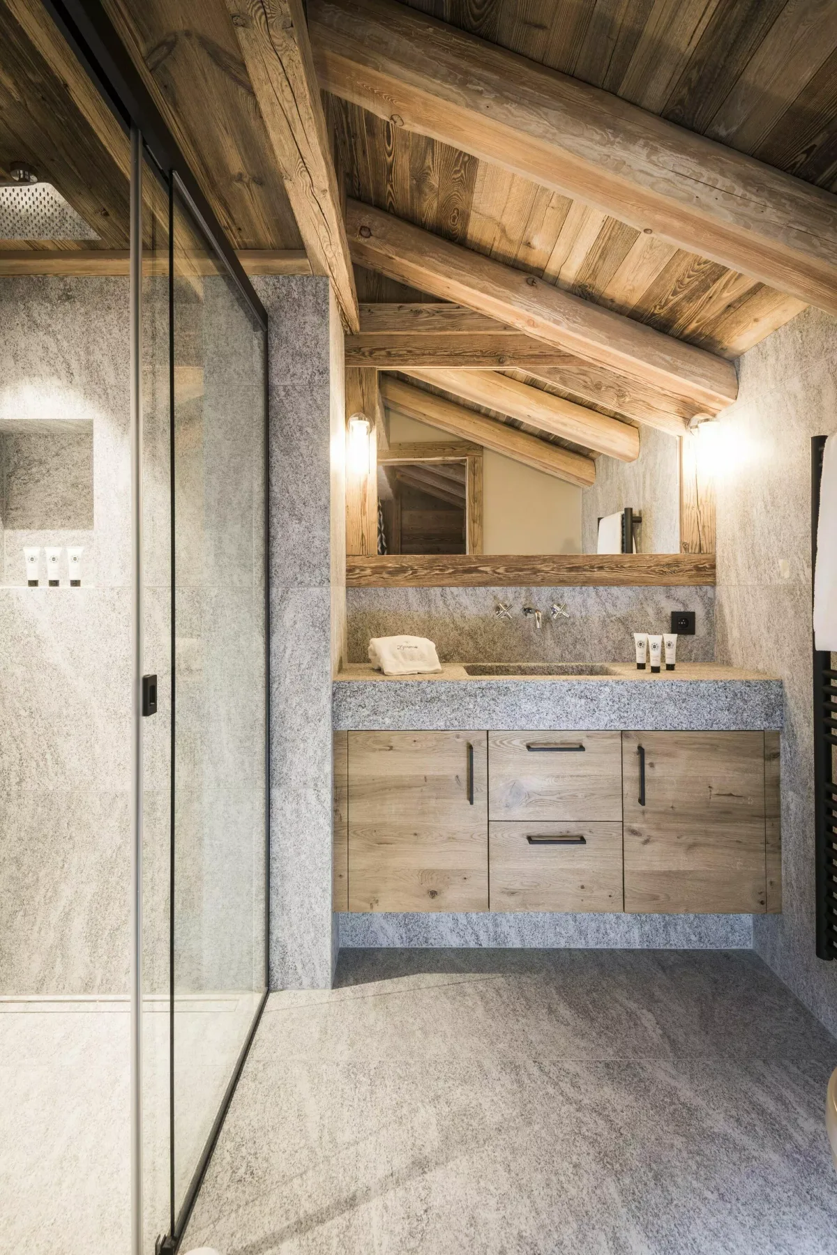 Un baño rústico con un mueble de madera, un espejo amplio y una ducha de cristal.