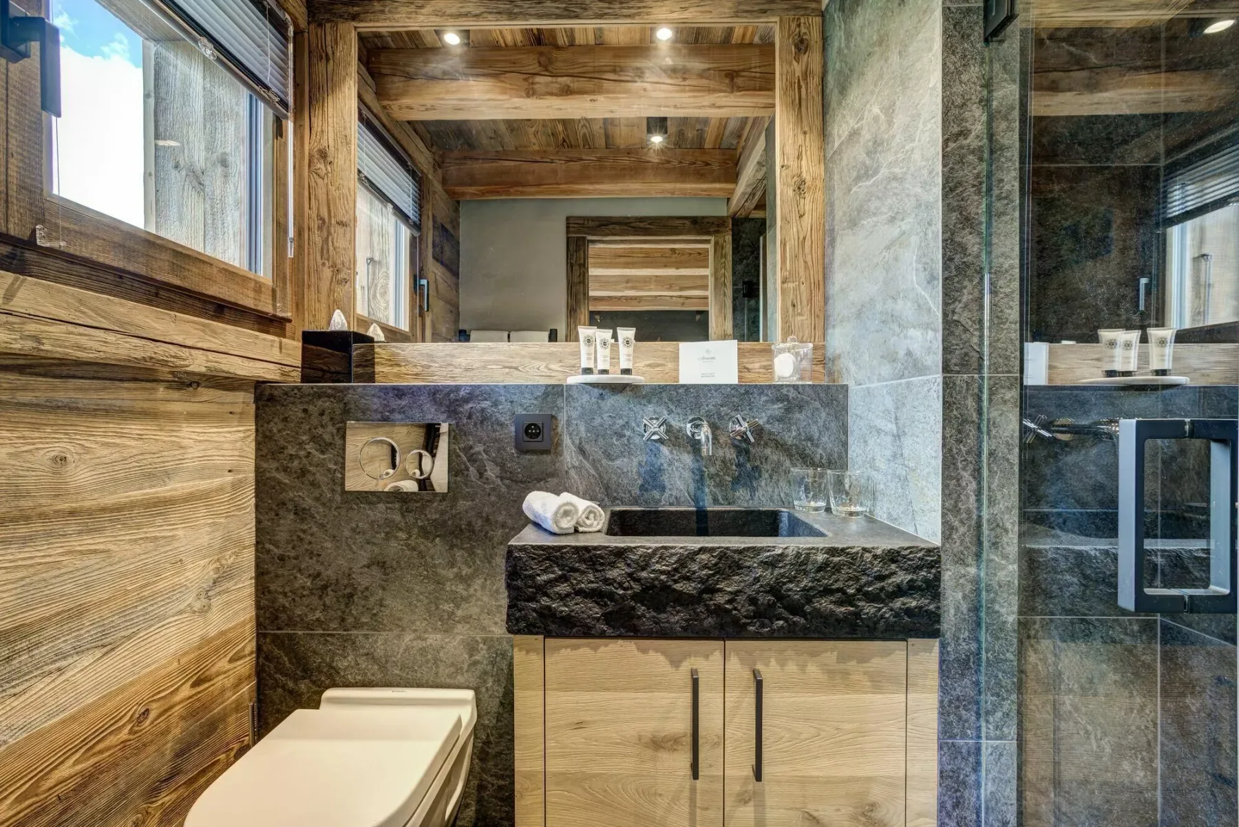 Un baño rústico con lavabo de piedra, fregadero e inodoro.