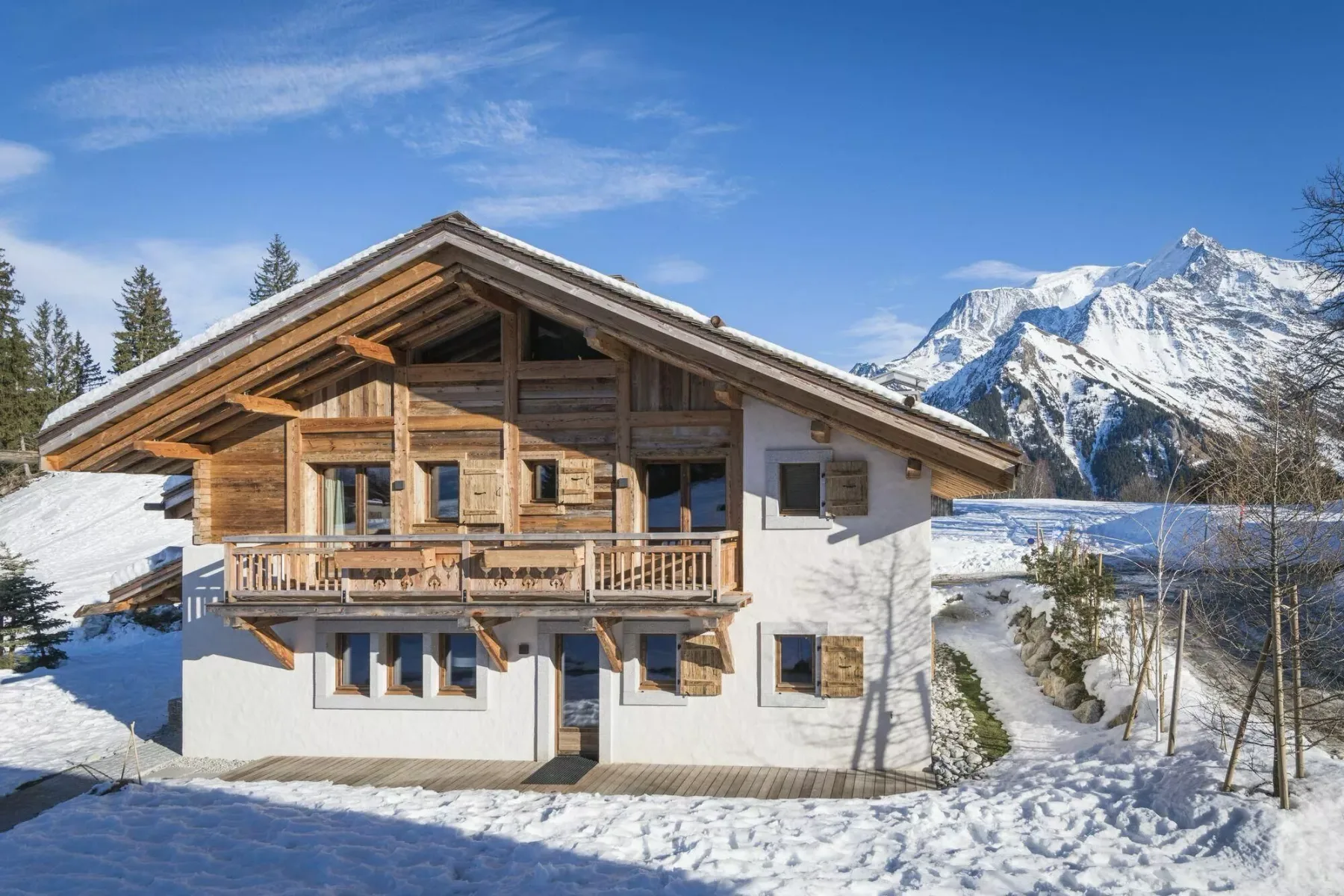 Una casa de estilo chalet se alza en un paisaje nevado bajo una montaña.
