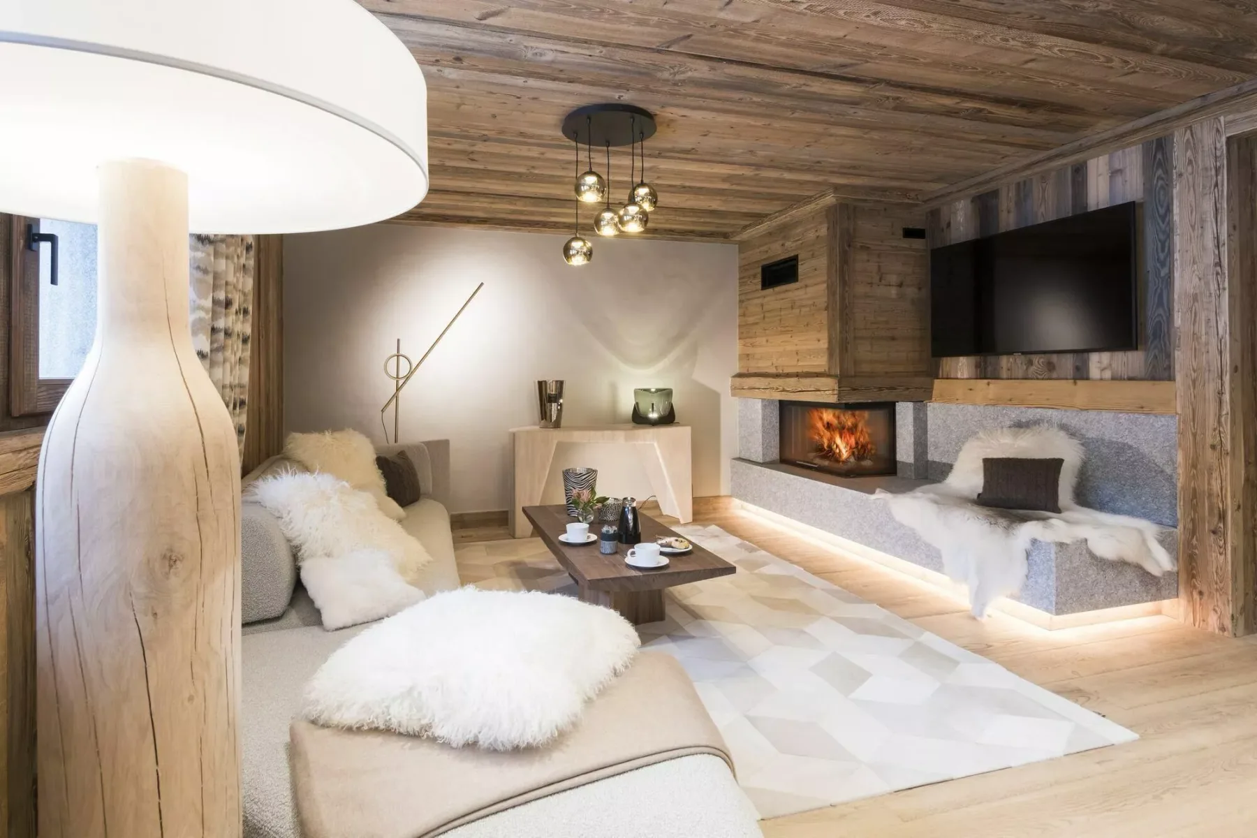 Una acogedora sala de estar con asientos bajos, una chimenea y un televisor grande.