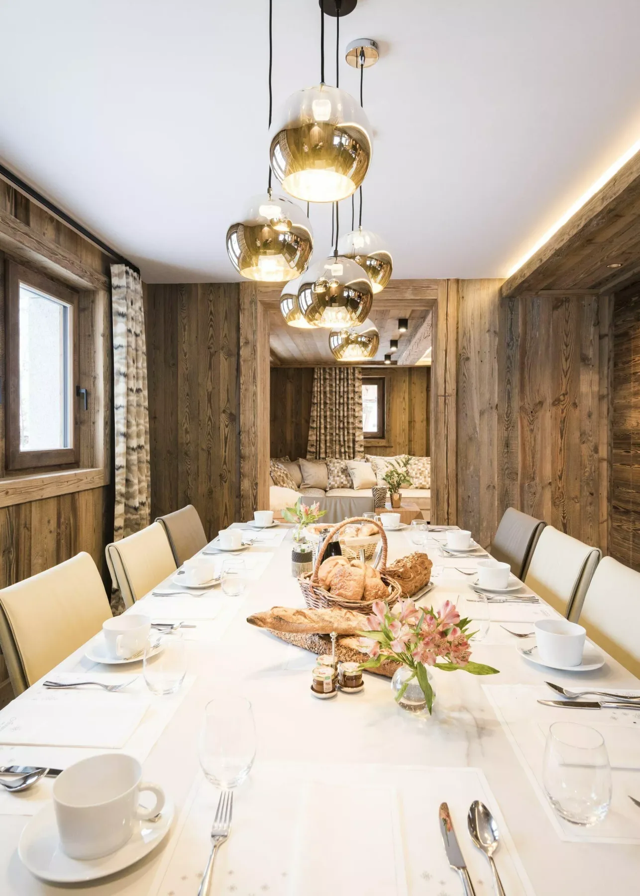 Un comedor con una mesa larga puesta con platos, tazas y flores.