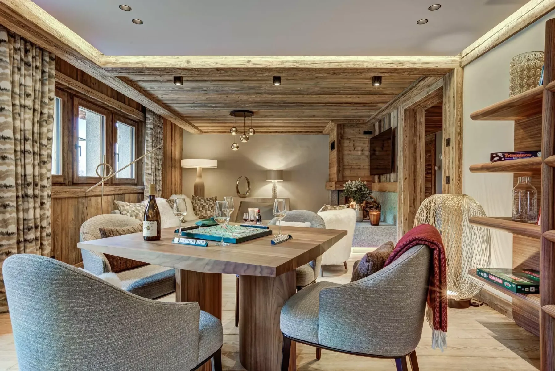 Comedor con una mesa de madera, asientos tapizados y estanterías empotradas.