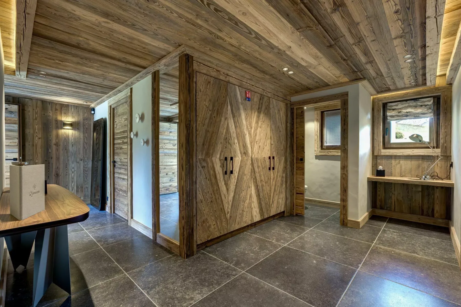 Un recibidor interior revestido de madera, con suelo de baldosas y almacenamiento integrado.
