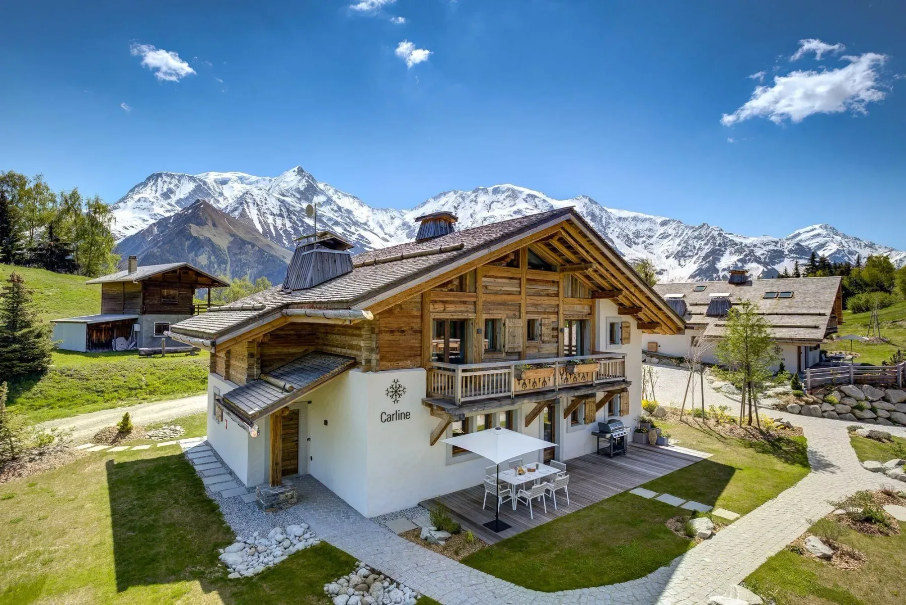 Un edificio de estilo chalet con balcones de madera se alza frente a montañas nevadas.