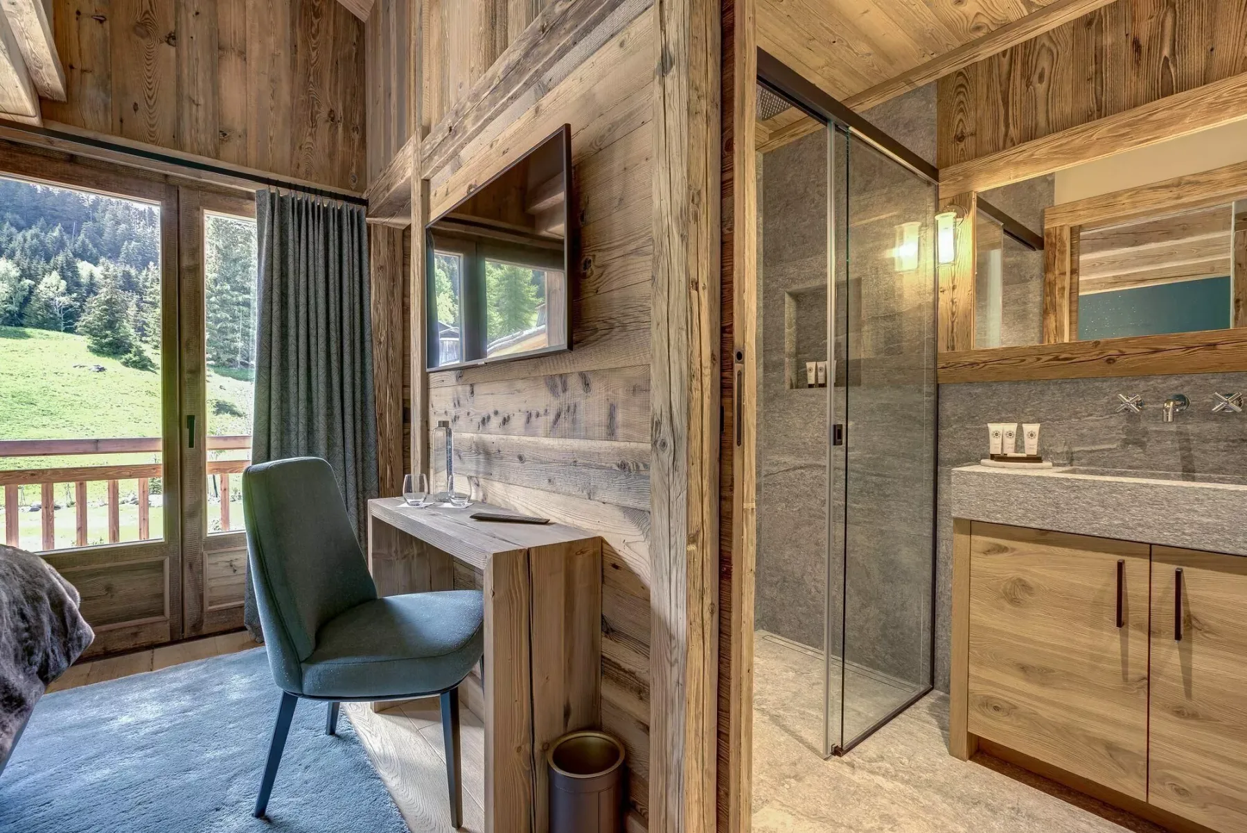 Una zona de dormitorio revestida de madera, con escritorio, asiento y un baño contiguo.