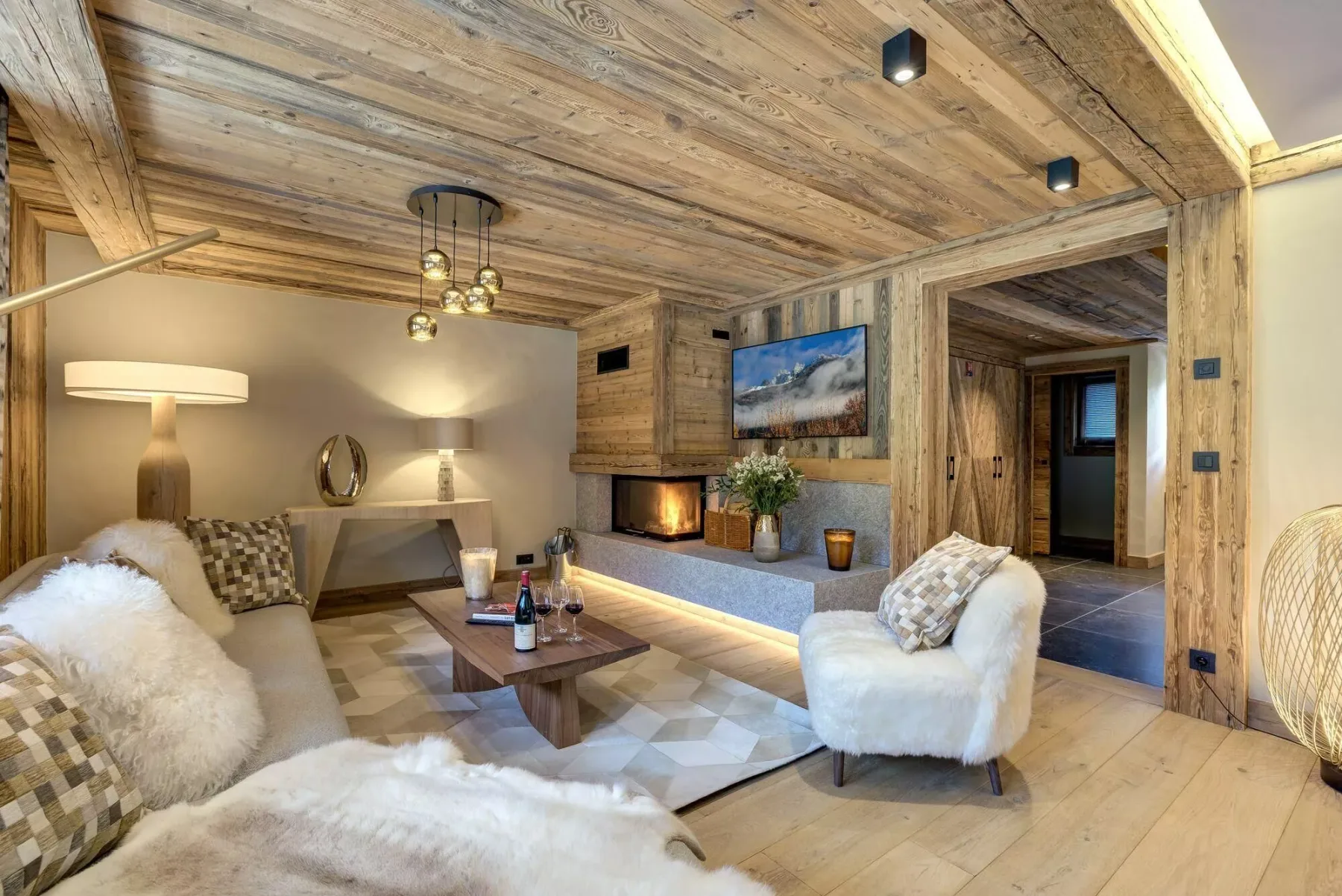 Una sala de estar revestida de madera con asientos, una mesa de centro y una chimenea empotrada.