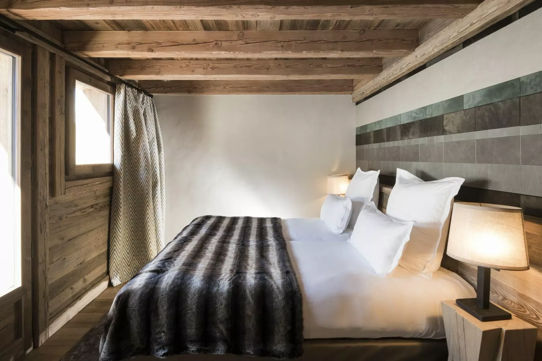 Un dormitorio con una cama bien tendida y una manta oscura.