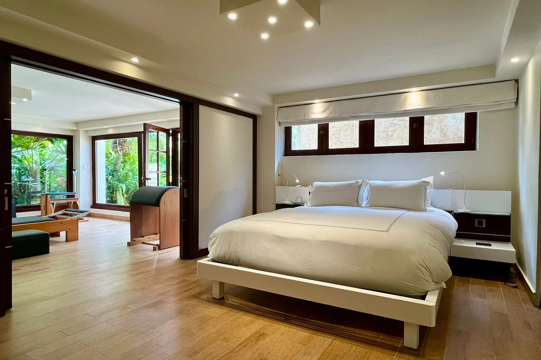 A bedroom with a large bed and high horizontal windows.