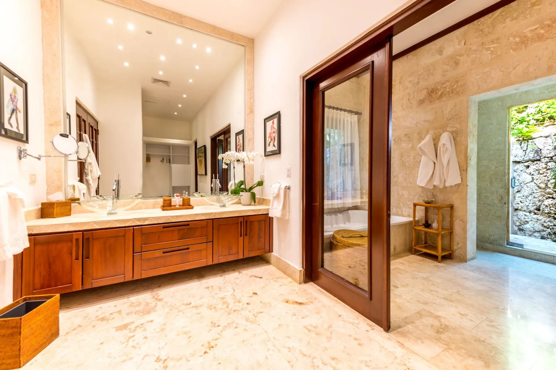 A bright bathroom with a long vanity and a large mirror.