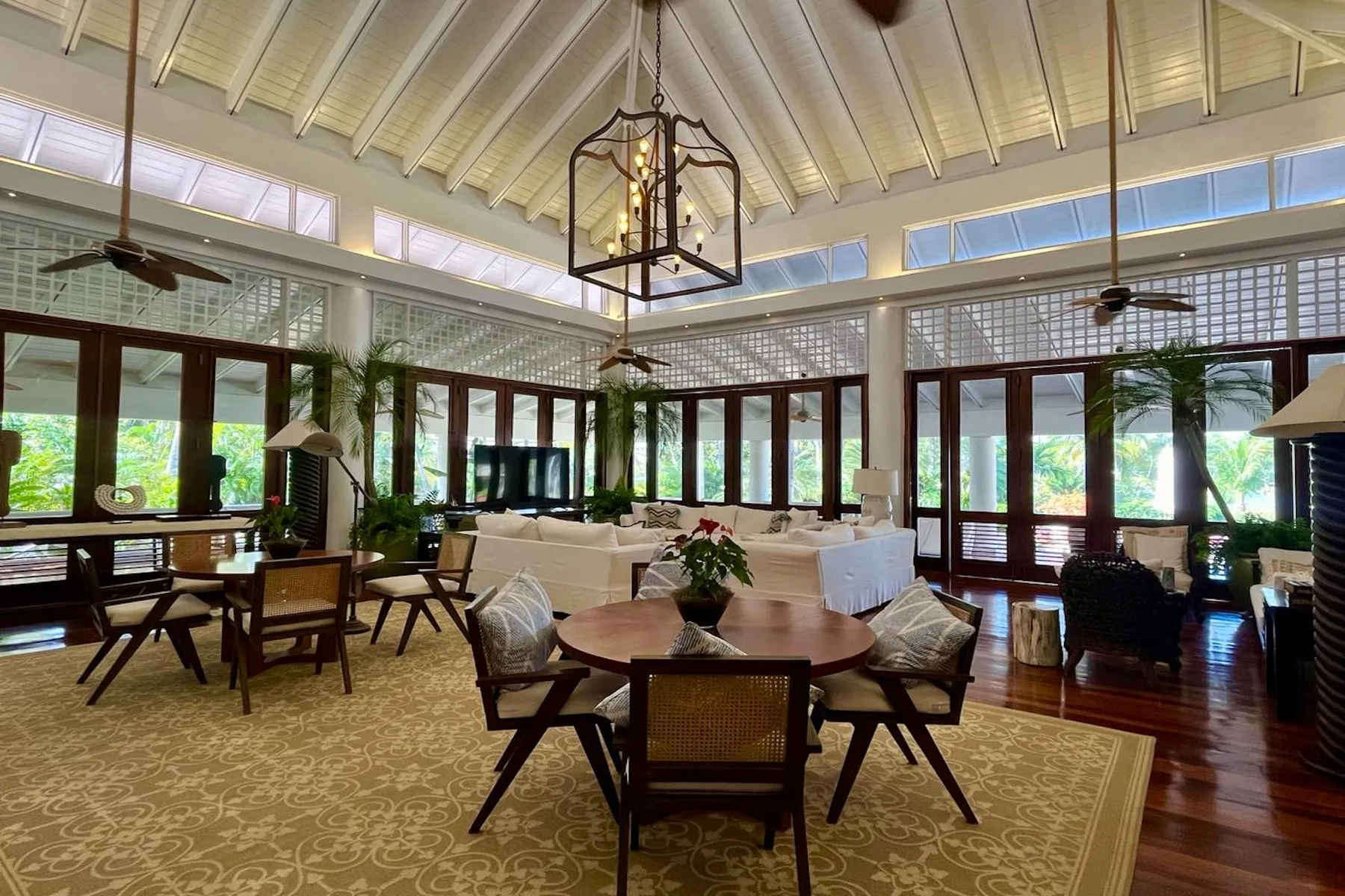 A bright living room with seating around a table and windows along the walls.