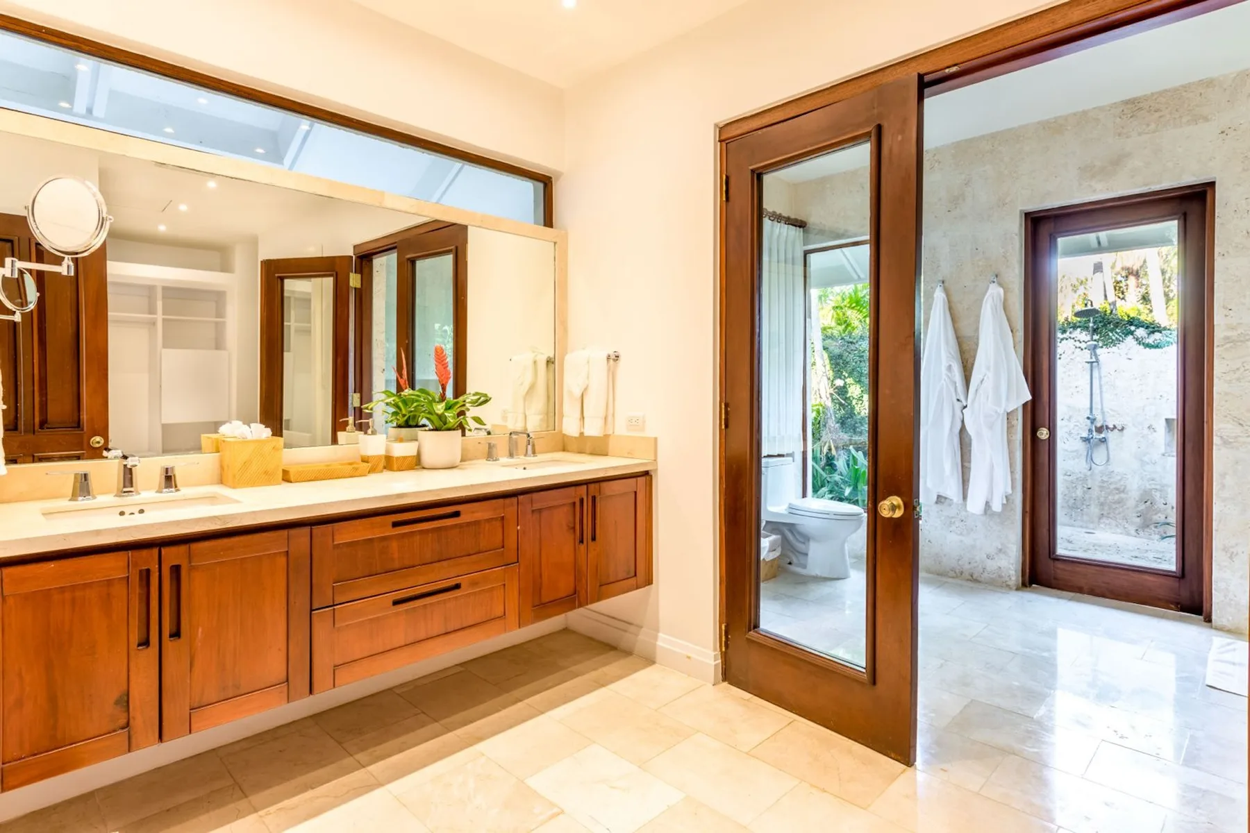 A bathroom with a long vanity and an adjoining shower area.