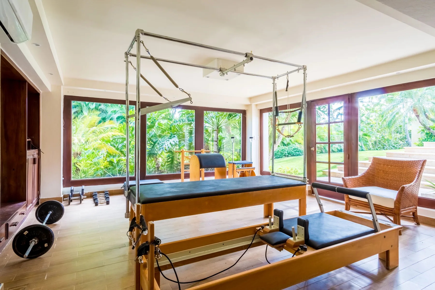 A bright exercise room with weight-training equipment and large windows.