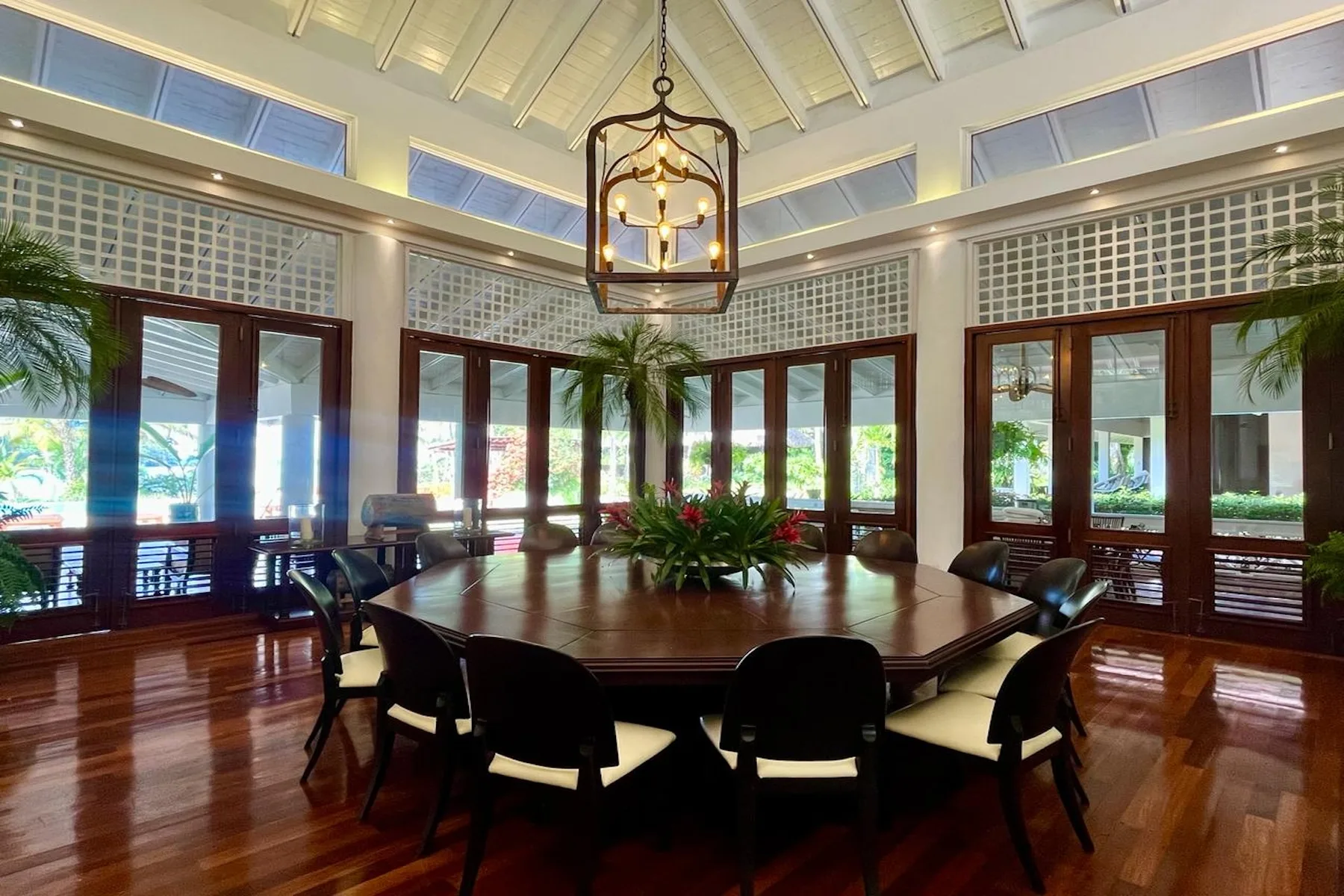 A bright dining room with a round table and chairs beneath a hanging light.