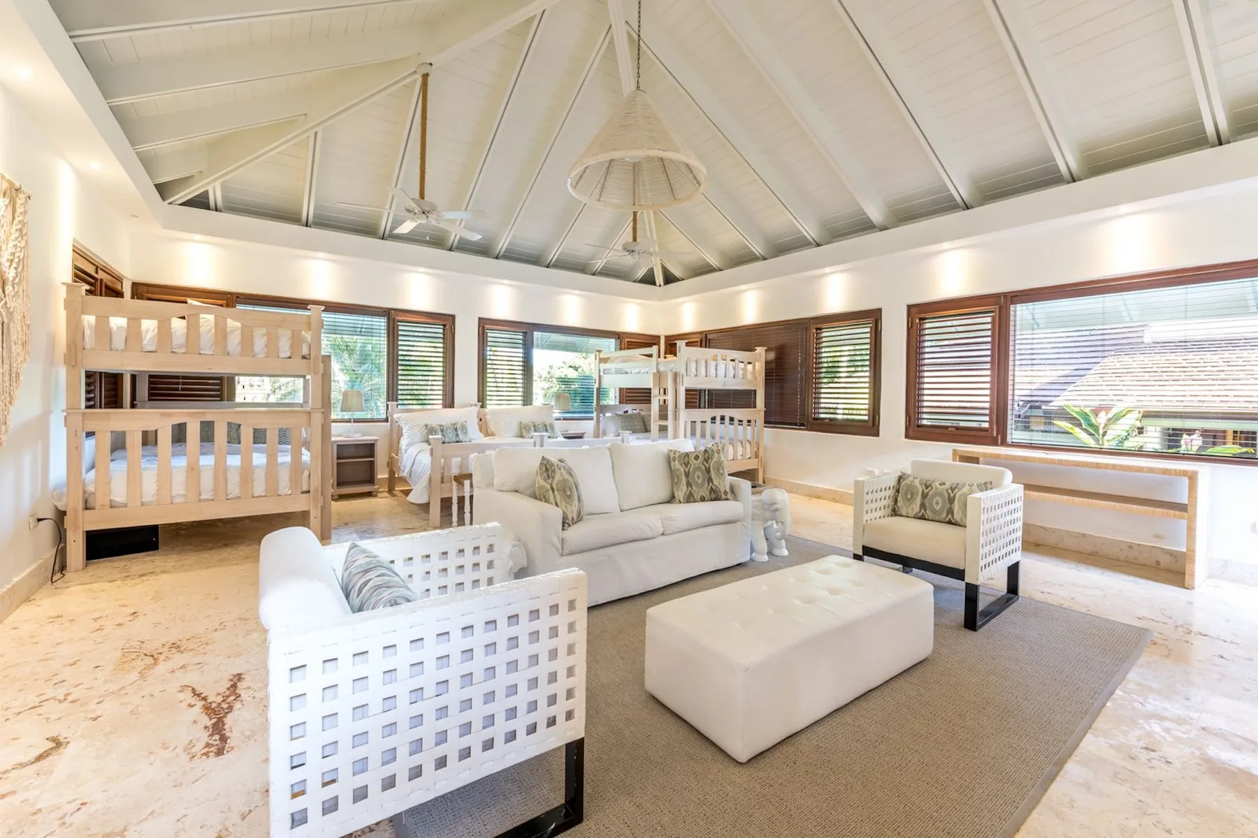 A bright living room with white seating arranged around a low ottoman.