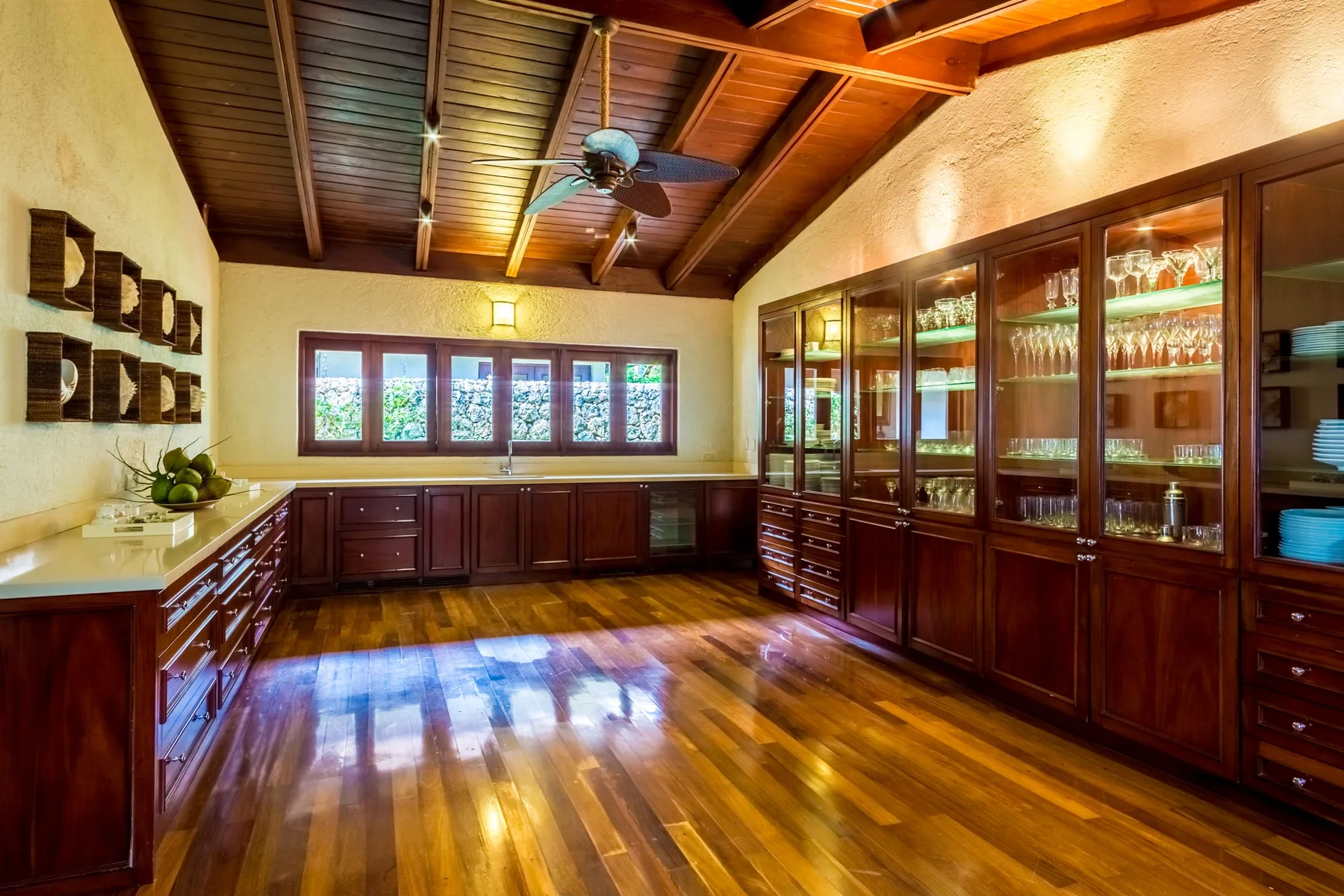 A spacious kitchen with dark wooden cabinets, glass-front cupboards, and a polished wood floor.