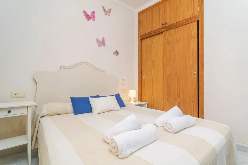 A bedroom with a neatly made bed and folded towels.