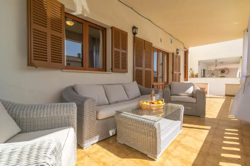 A covered patio seating area with wicker furniture and a low table.
