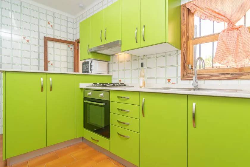 A bright kitchen with lime-green cabinets, a countertop, and a window.