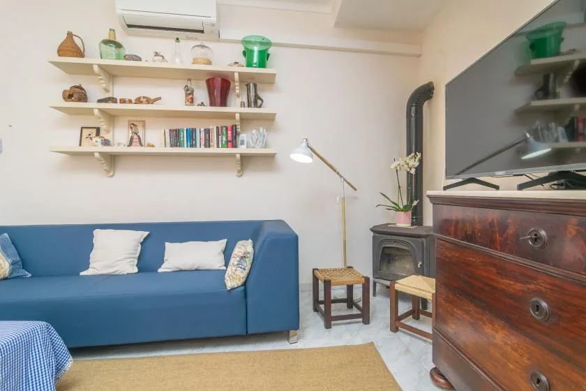 A living room with blue seating, wall shelves, and a television on a wooden cabinet.