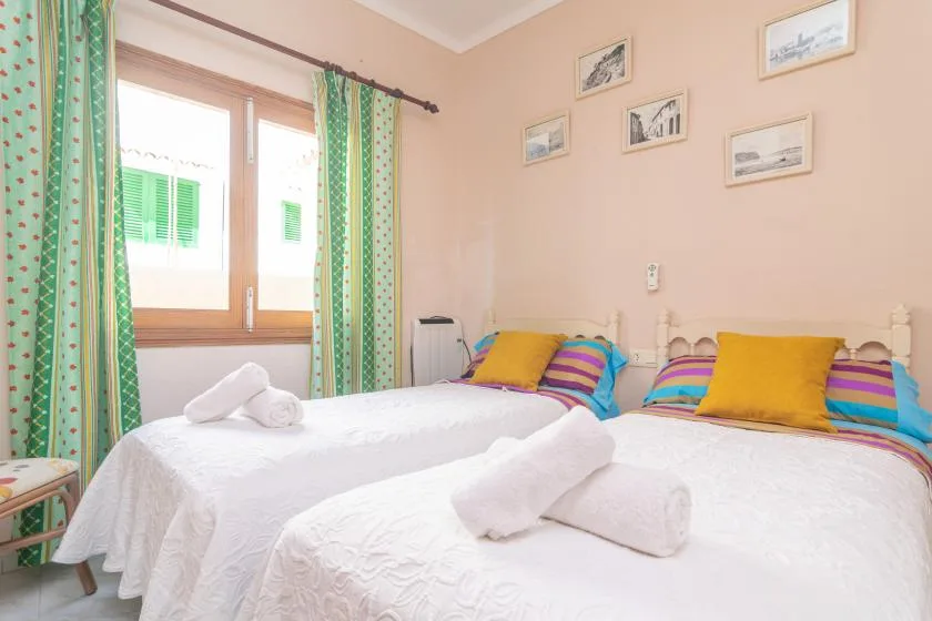 A bedroom with two beds dressed in white linens and colorful pillows.