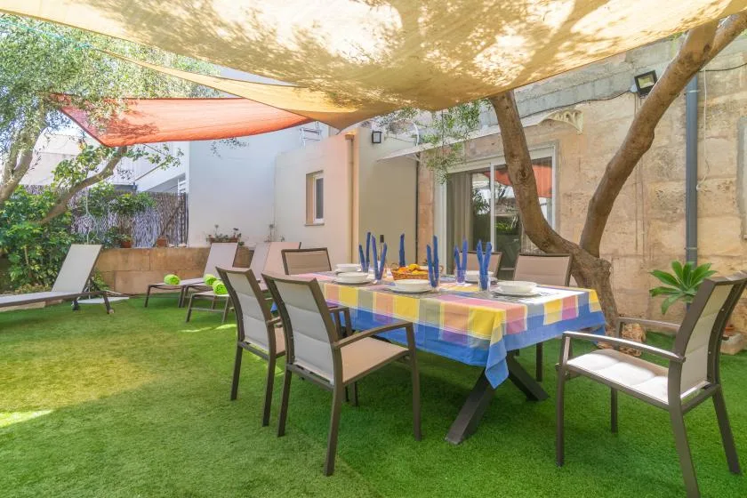 An outdoor dining area with a colorful tablecloth and shaded seating.