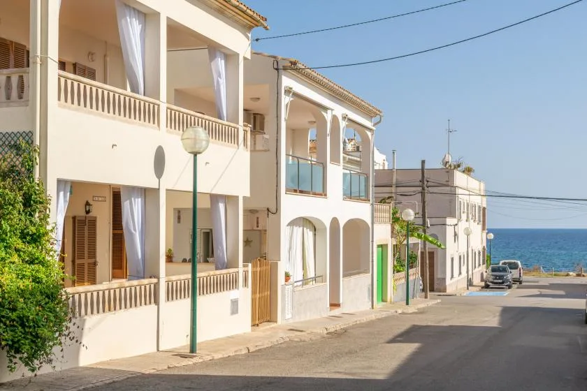 A seaside street with pale apartment buildings and the ocean visible at the end.